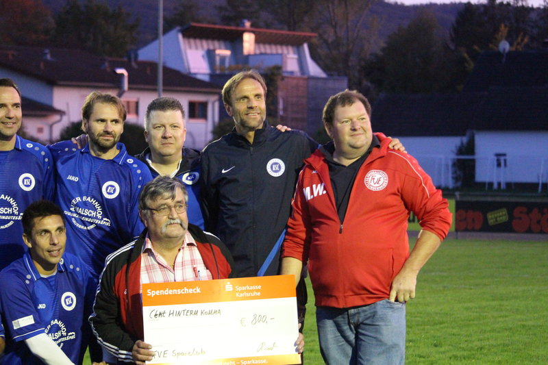 Eine Gruppe von Männern steht auf einem Fußballfeld und hält einen Scheck in den Händen