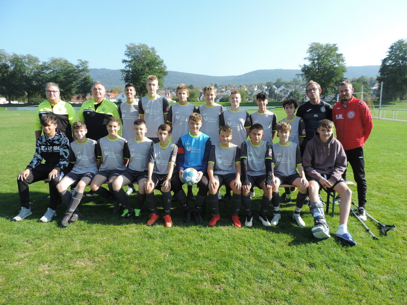 Die Spieler einer Fußballmannschaft stehen auf dem Feld und lächeln für ein Teamfoto.
