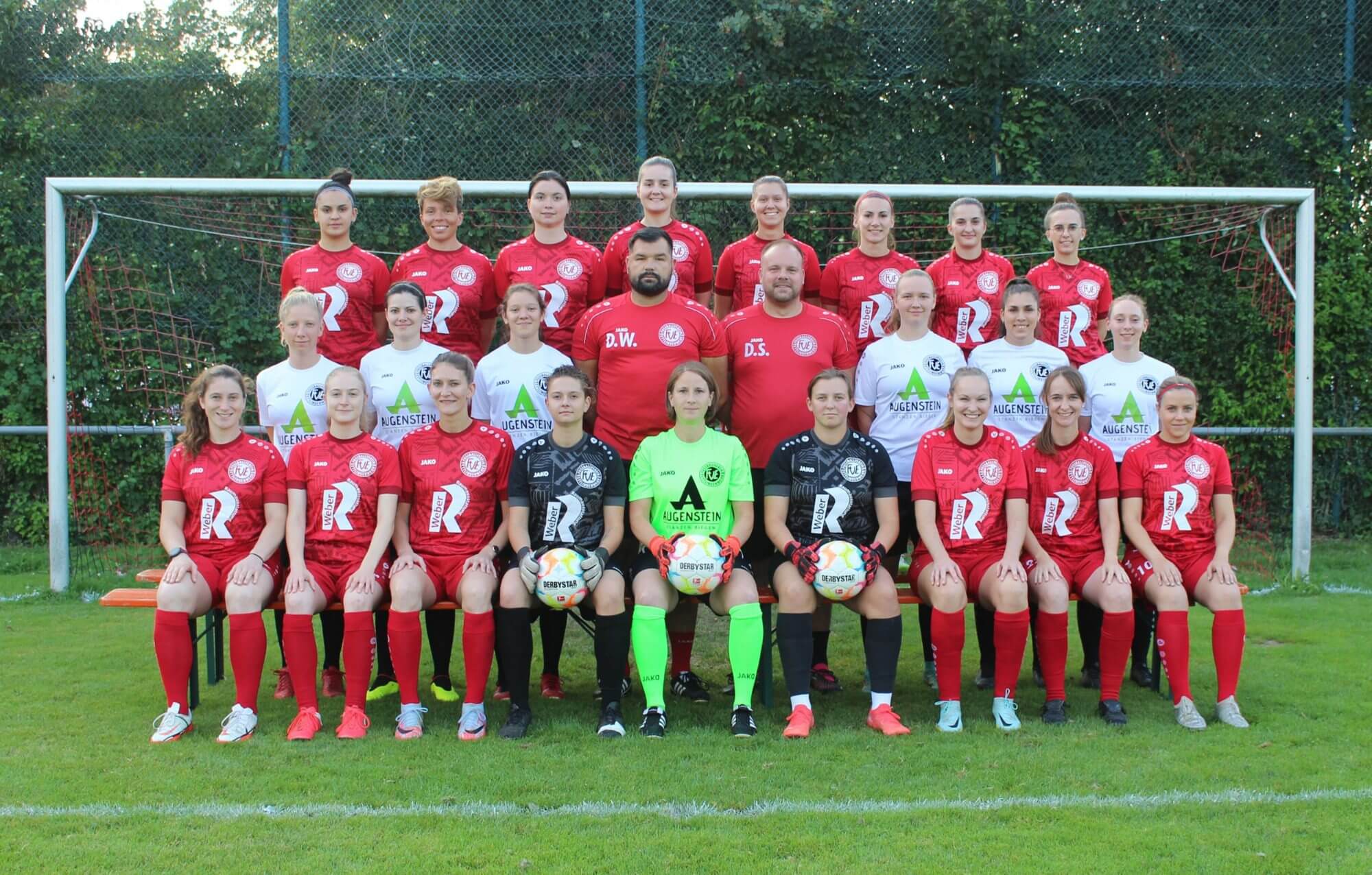 Eine Gruppe von Männern posiert lächelnd vor einem Fußballtor für ein Foto