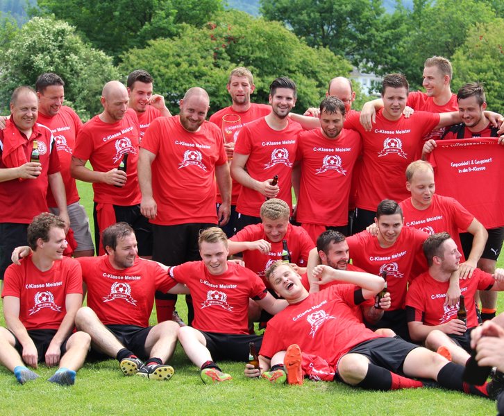 Männer in roten Shirts versammeln sich, lächeln und posieren für ein Gruppenfoto
