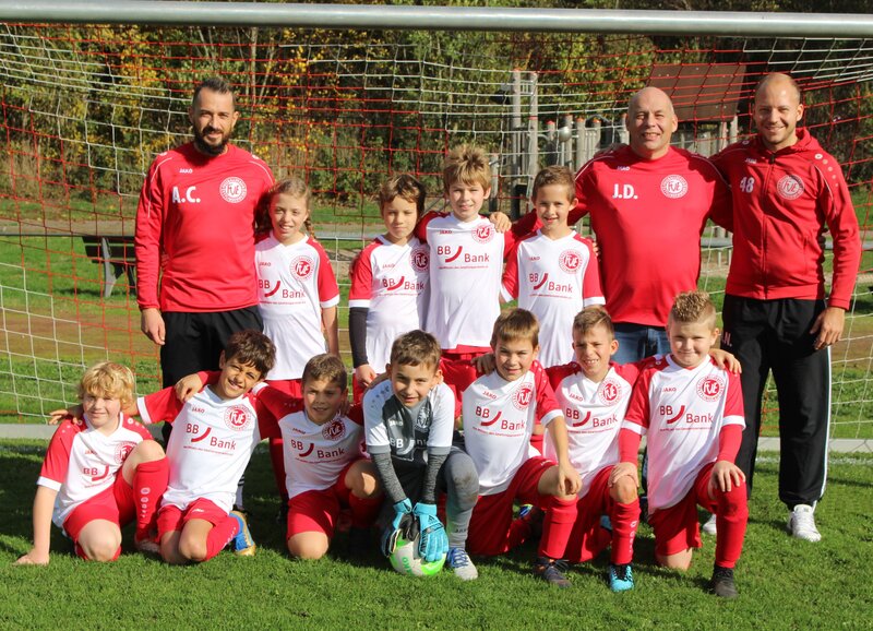 Jungen in roten und weißen Fußballuniformen posieren gemeinsam auf dem Sportplatz.