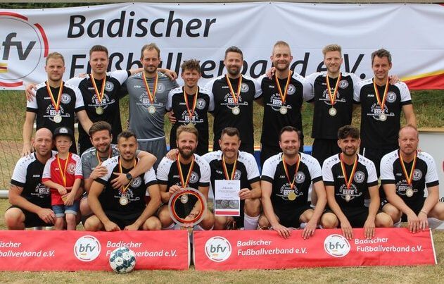Die Männerfußballmannschaft posiert stolz mit ihren Medaillen für ein Gruppenfoto