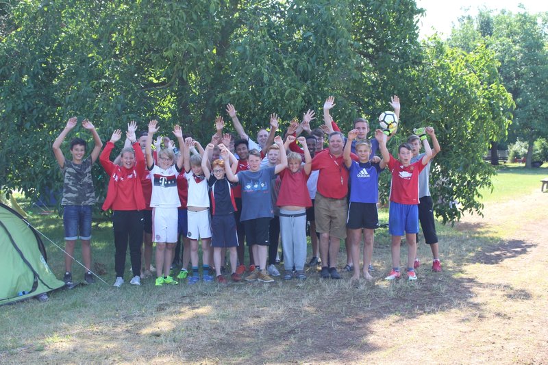 Eine Gruppe von Menschen steht vor einem Zelt und posiert für ein Foto in der Natur