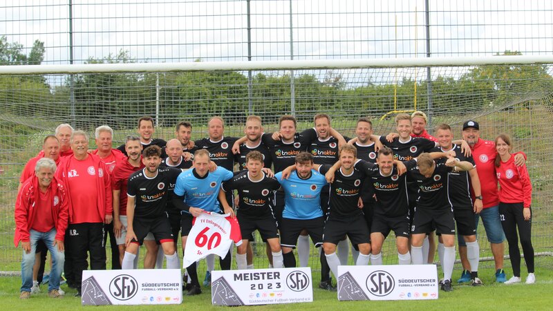 Eine Gruppe von Männern in schwarzen und roten Fußballtrikots steht zusammen auf dem Spielfeld.