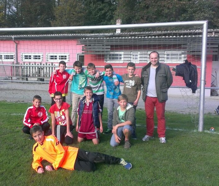 Eine fröhliche Gruppe von Jugendlichen posiert vor einem Fußballtor für ein Erinnerungsfoto.