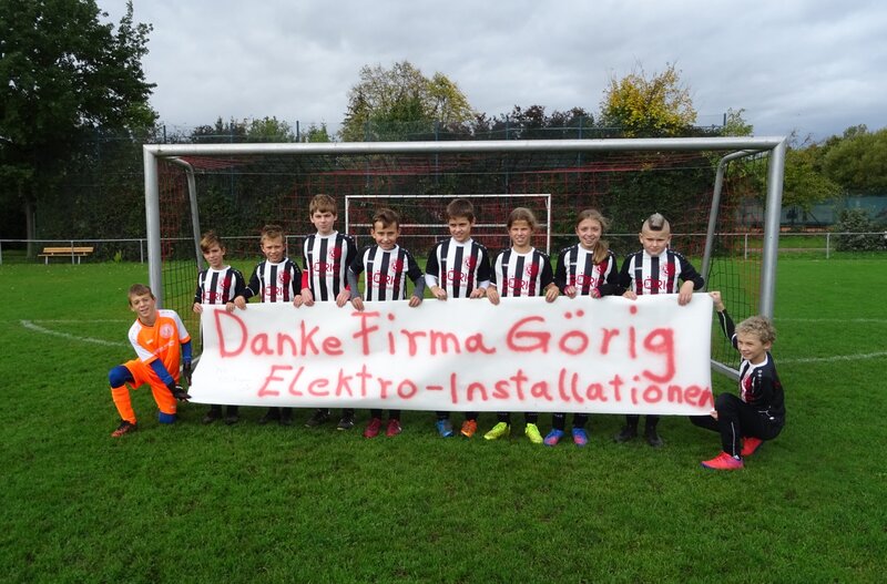Eine Jugendfußballmannschaft posiert vor einem Tor und hält ein Transparent mit der Aufschrift „Danke Firma Görig Elektro-Installationen“.