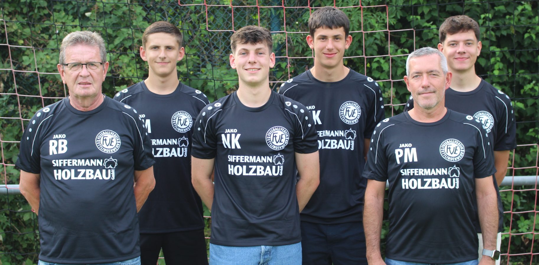 Sechs Männer stehen vor einem Netz. Sie tragen passende schwarze Sportshirts mit dem Aufdruck „SIFFERMANN HOLZBAU“. Sie befinden sich im Freien, im Hintergrund ist grünes Laub zu sehen. Drei Männer stehen vor ihnen, drei stehen hinter ihnen.