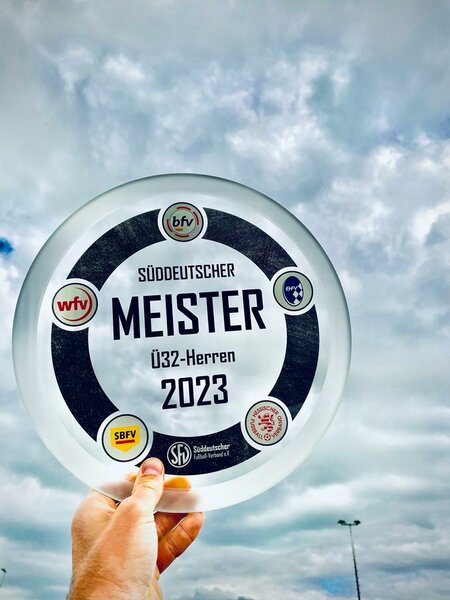 Eine Person zeigt stolz eine Glasplatte mit der Inschrift mester 2023.